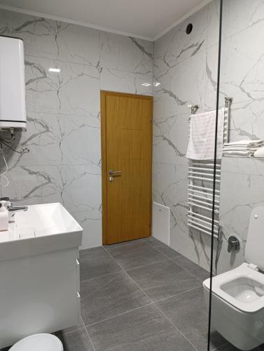 a bathroom with a toilet and a wooden door at Villa Majida Ilidža in Sarajevo