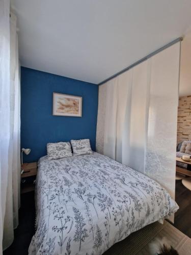 une chambre avec un lit avec un mur bleu dans l'établissement Bright apartment 10 minutes from Cannes, au Cannet