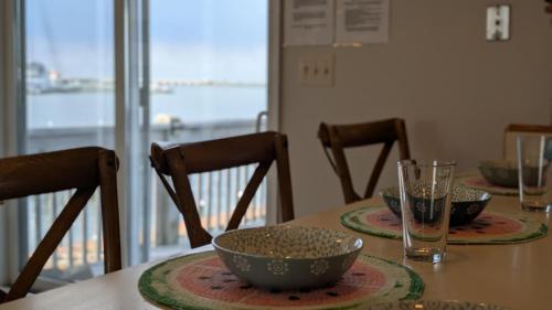a table with three chairs and bowls on it at Bay Front Home - Watch the sun rise over LBI. Pier for Boat/Swim/SUP/Kayak/Crab in Manahawkin