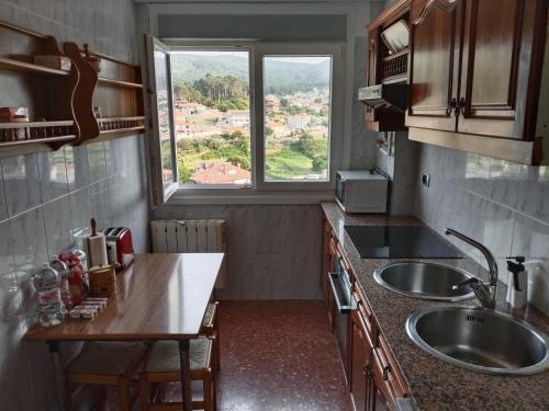 une petite cuisine avec un évier et une fenêtre dans l'établissement Precioso piso con vistas a las Islas Cíes, à Baiona