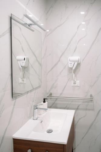 a white bathroom with a sink and a mirror at Calabreeze in Villa San Giovanni
