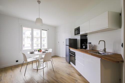 une cuisine avec des armoires blanches et une table et des chaises dans l'établissement T2 rénové hyper centre vue dégagée, à Grenoble