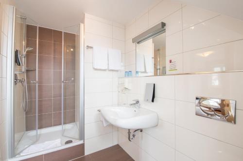 a white bathroom with a sink and a shower at Stiftsgut Keysermühle in Klingenmünster
