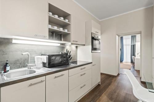 a white kitchen with a sink and a microwave at Apartments I 5 Min to Millennium City Mall and Handelskai U6 in Vienna