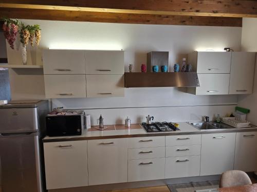 a kitchen with white cabinets and a sink and a microwave at Da Tiffany a Bussolengo Verona in Bussolengo