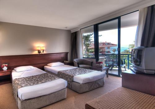a hotel room with two beds and a television at Golden Lotus Hotel in Kemer