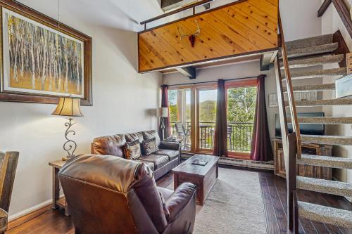 a living room with a couch and a staircase at Emerald Views at the West in Steamboat Springs