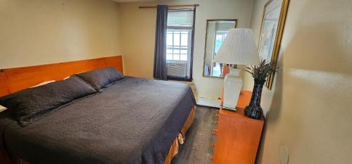 a bedroom with a bed and a lamp and a window at Ships Inn in Hampton
