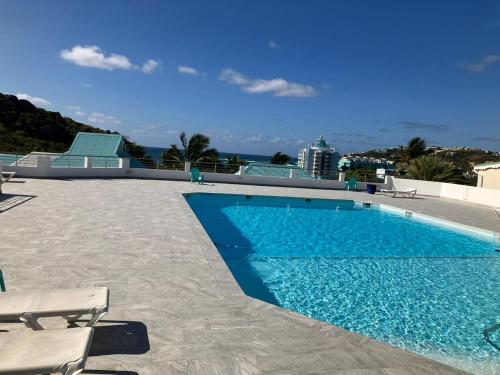 a swimming pool with two chairs next to it at Beautiful F2 in a blue beach residence in Oyster Pond