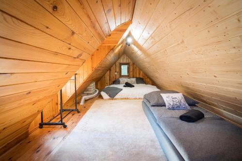 a room with two beds in a wooden attic at Domek na Skarpie nr 2 Łutynowo in Łutynowo