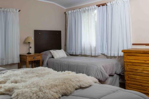 a bedroom with two beds and a dresser and curtains at Hotel Le Charme in San Carlos de Bariloche