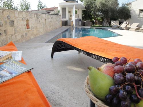 a basket of fruit on a table next to a pool at Kaizer Agrotourism in Amargeti
