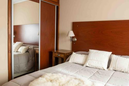a bedroom with a large white bed and a mirror at Hotel Le Charme in San Carlos de Bariloche
