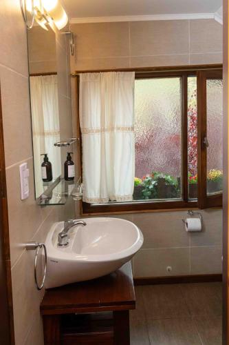 a bathroom with a sink and a window at Hotel Le Charme in San Carlos de Bariloche