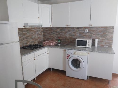 a kitchen with a washing machine and a microwave at Casa Santa Maria - apartamento C in Ermidas
