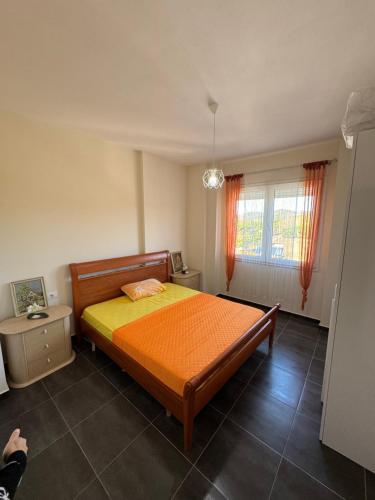 a bedroom with a bed and a window with orange curtains at Breeze of Lalëz in Lalzit Bay