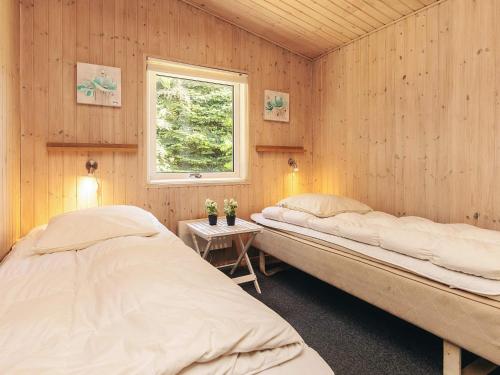 two beds in a room with wooden walls at 4 star holiday home in Væggerløse in Marielyst