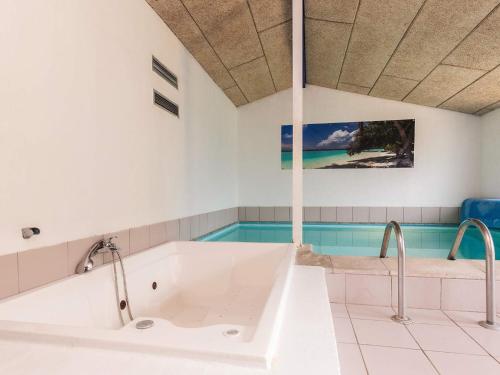 a bathroom with a tub and a swimming pool at 4 star holiday home in Væggerløse in Marielyst