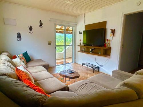a living room with a couch and a television at Casa Sobre as Nuvens - Ideal para Casal ou Família in Campos do Jordão