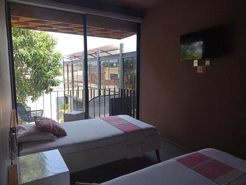 a room with two beds and a large window at Hotel Momotus Tuxtla - Desayuno opcional in Tuxtla Gutiérrez