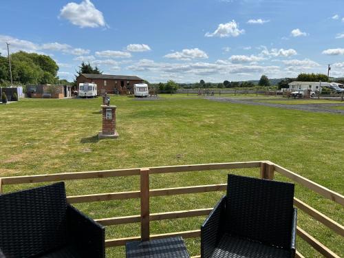 two chairs on a fence with a field and a park at Dolafon Luxury Glamping Pod 2 With Hot Tub in St Asaph