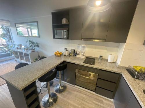 a kitchen with a counter and some stools in it at Departamento cerca Movistar Arena in Santiago