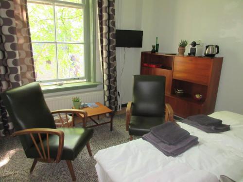 a bedroom with a bed and two chairs and a window at Guesthouse Groenmarkt in Middelburg