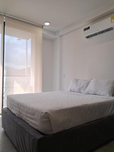 Una cama en un dormitorio con una ventana grande. en Tropical Oasis Suite, en Santa Marta