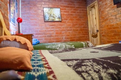 a room with a brick wall and a bed at Hostal La Casa Amarilla City in Baños