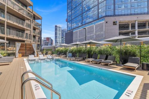a swimming pool with chairs and umbrellas on a building at Skyline Nights in Downtown Nashville Walk to Broadway with Pool and Gym in Nashville