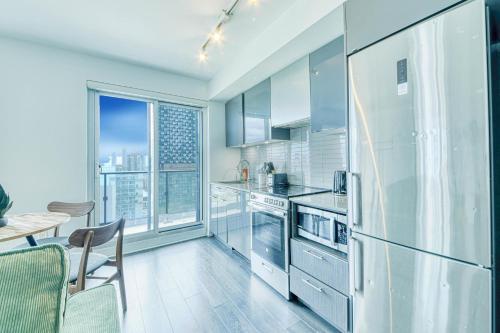 a kitchen with stainless steel appliances and a large window at RivetStays - The Jarvis in Toronto