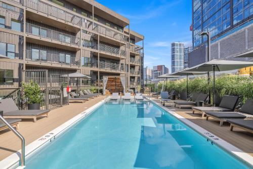 an outdoor swimming pool with lounge chairs and a building at Skyline Nights in Downtown Nashville Walk to Broadway with Pool and Gym in Nashville