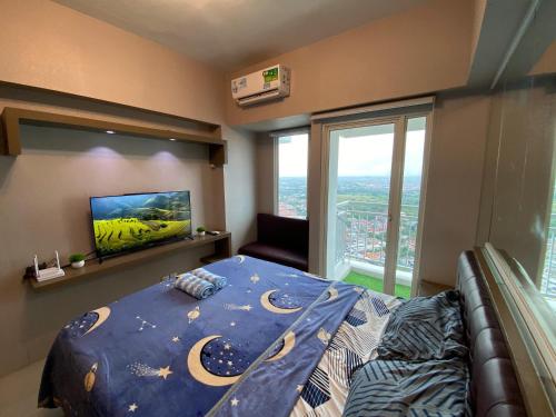 a bedroom with a bed and a flat screen tv at Pakuwon Mall Apartemen Anderson Orchard Tanglin Benson by AquHome in Surabaya