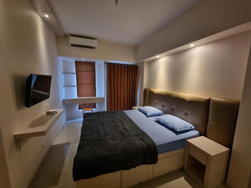 a bedroom with a large bed and a television at Pakuwon Mall Apartemen Anderson Orchard Tanglin Benson by AquHome in Surabaya