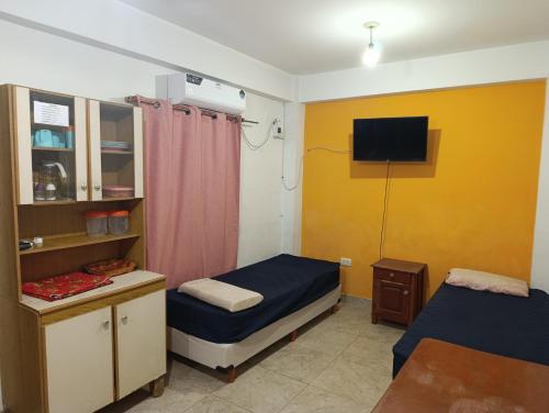 Una habitación con dos camas y un televisor en la pared. en Hospedaje Turisticos., en Libertador General San Martín