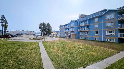 a large blue apartment building with a grass yard at Misty Mountain Inn & Suites in Grande Cache
