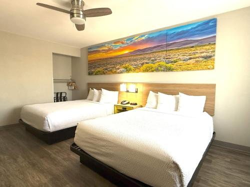 a hotel room with two beds and a painting on the wall at Days Inn by Wyndham Yuma in Yuma