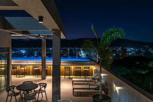a patio with tables and chairs on a building at night at Elegance - Piscina Aquecida - Apartamento para 4 pessoas em Bombinhas in Bombinhas