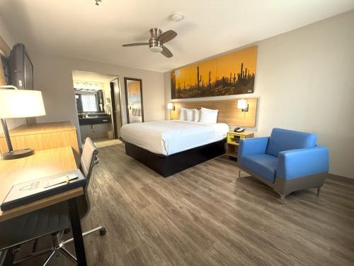 a hotel room with a bed and a blue chair at Days Inn by Wyndham Yuma in Yuma