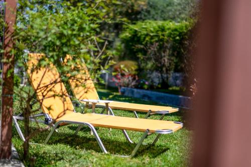 two chairs and a bench in the grass at Ridomo Sea View Villas Camellia & Jasmine in Avia