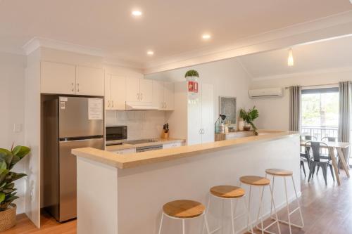 a kitchen with white cabinets and a counter with stools at Outrigger Bay in Byron Bay
