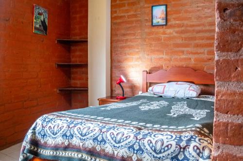 a bedroom with a bed and a brick wall at Hostal La Casa Amarilla City in Baños