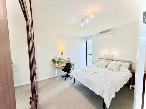 a white bedroom with a bed and a desk at Leafy 3-Bedroom Escape to Nature-Air Conditioned with Smart Entry in Ferny Hills