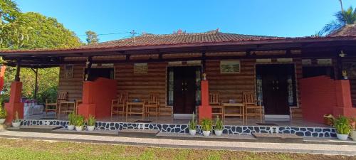a wooden cabin with tables and chairs in front at Gosela Bali in Munduk