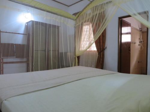 a bedroom with a white bed and a window at Bentota Home Stay in Bentota