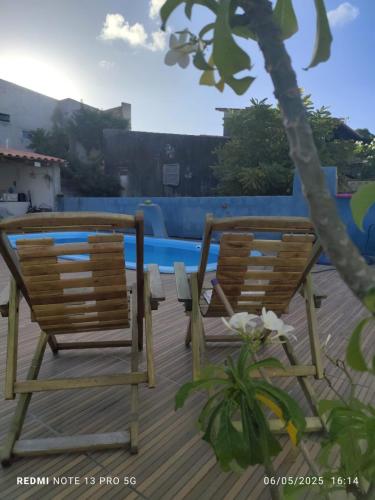 dos sillas sentadas en una terraza junto a una piscina en Pousada Casa BiGui, en Santa Cruz Cabrália
