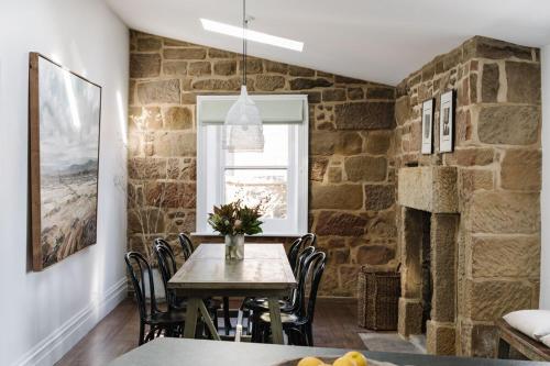 a dining room with a table and a stone wall at Raffah House in Oatlands