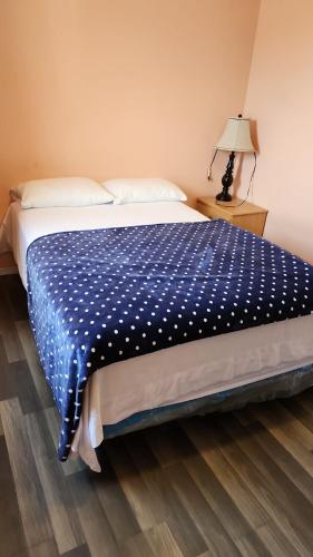 a bedroom with a bed with a blue comforter at Balgonie Motor Inn in Pilot Butte