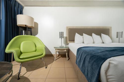 a hotel room with a bed and a green chair at Windward Passage Hotel in Charlotte Amalie