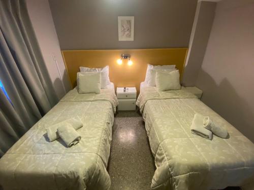 two beds in a hotel room with towels on them at HOTEL JUAN b JUSTO GARDEN in Mendoza